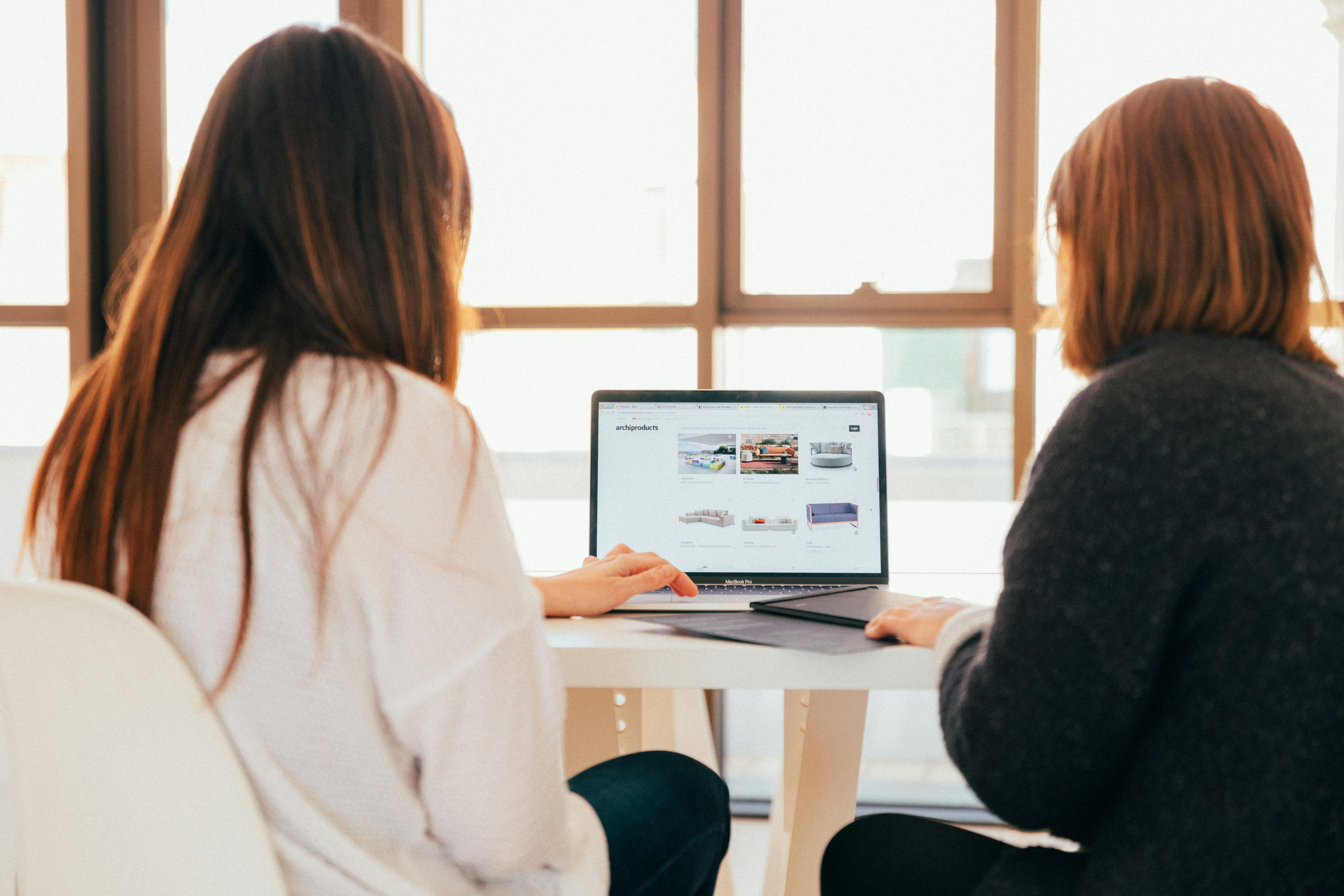 Two women talking while looking at laptop computer.