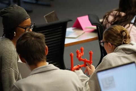 an image of students holding an orange 3-D printed phylogenetic tree and examining its structure